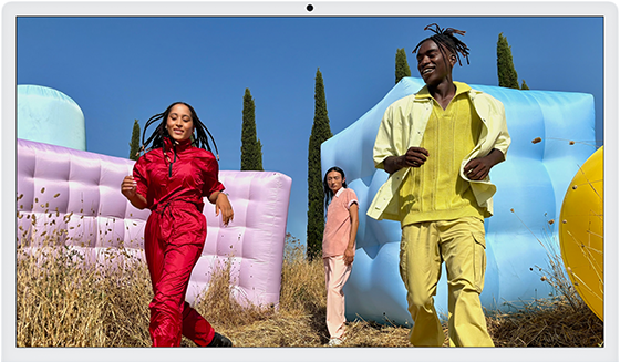 Three people in bright outfits, surrounded by colourful inflatable shapes