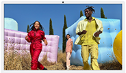 Three people in bright outfits, surrounded by colourful inflatable shapes