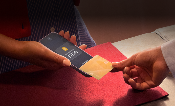 A hand taps a credit card to an iPhone to complete a transaction