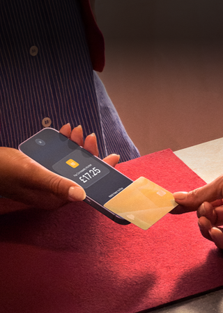 A hand taps a credit card to an iPhone to complete a transaction