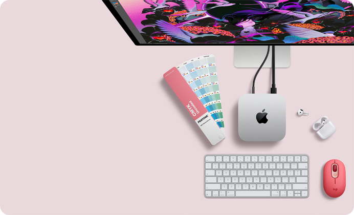 Mac mini, top, silver aluminium, rounded corners, glossy black Apple logo centred, connected by cord, Studio Display partially visible on top, AirPods 4, open, Pantone colour swatches, and red Logitech keyboard and mouse