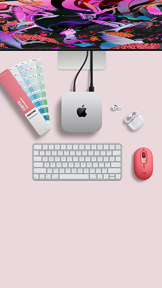 Mac mini, top, silver aluminium, rounded corners, glossy black Apple logo centred, connected by cord, Studio Display partially visible on top, AirPods 4, open, Pantone colour swatches, and red Logitech keyboard and mouse